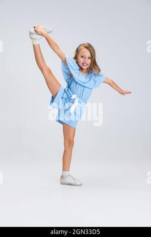 Portrait complet de mignonne fille dans des vêtements décontractés jouant isolé sur fond blanc de studio. Concept d'enfance heureuse. Enfant ensoleillé. Semble heureux Banque D'Images