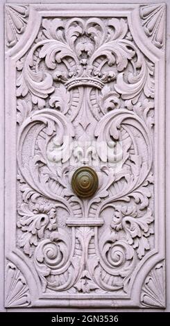 Vue rapprochée d'une porte de cour historique avec poignée de porte et sculptures en bois ornées de rose sombre Banque D'Images