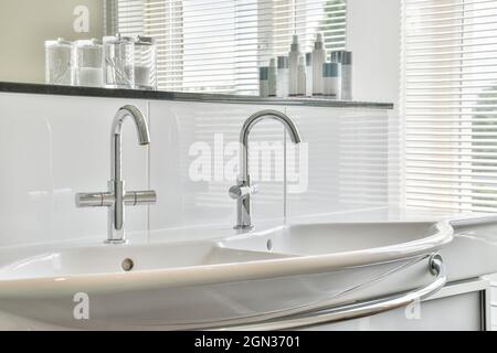 Double lavabo blanc moderne dans la salle de bains avec robinets conçus dans un style minimaliste dans l'appartement Banque D'Images