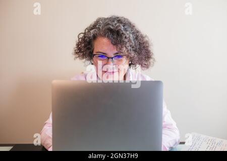 Femme d'affaires souriante, femme d'affaires en lunettes et écouteurs assis à une table avec un netbook Banque D'Images