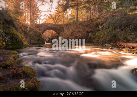 Paysage pittoresque pont en pierre au-dessus de la rivière dans le parc d'automne de la Sierra de Guadarrama en Espagne en journée Banque D'Images