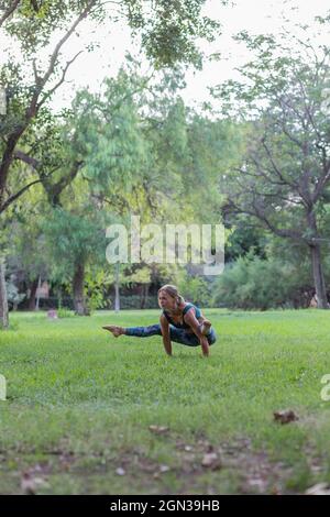 Femme ciblée dans une élégante activité en train de poser un pompier tout en pratiquant le yoga dans le parc pendant la journée Banque D'Images