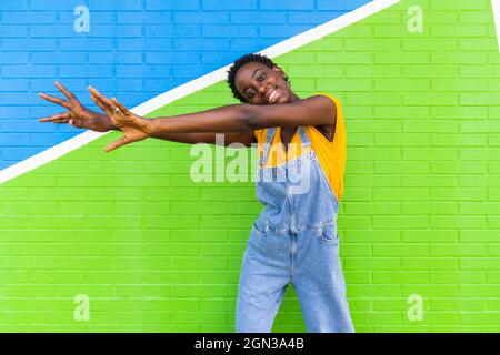Femme adulte souriante portant un chemisier en soie et un pantalon préparant un sac de thé dans une tasse en verre cuisine Banque D'Images