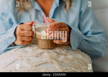 Crochez une femme adulte avec des cheveux ondulés en buvant un café savoureux tout en regardant vers l'avant dans la maison Banque D'Images