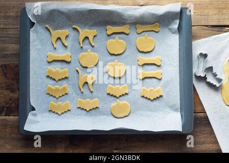 Biscuits de différentes formes pour Halloween sur une plaque de cuisson. Biscuits coupés avant la cuisson. Copier l'espace. Banque D'Images