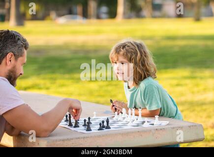 bonne famille de papa et garçon de fils jouant aux échecs sur la table dans le parc extérieur, concours d'échecs Banque D'Images