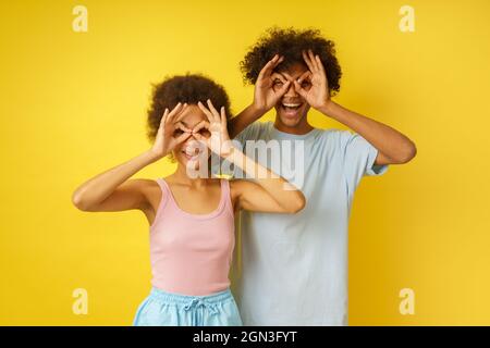 Couple heureux blague en faisant des lunettes avec leurs mains Banque D'Images