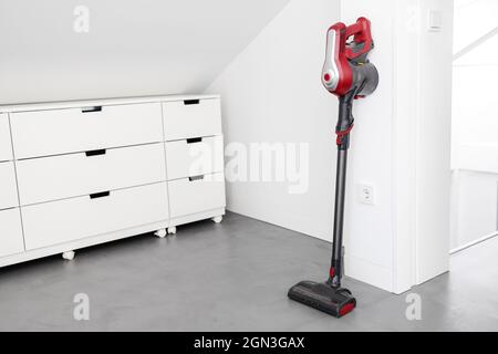 Aspirateur sans fil moderne appuyé sur un mur d'une pièce. Concept de devoir Banque D'Images