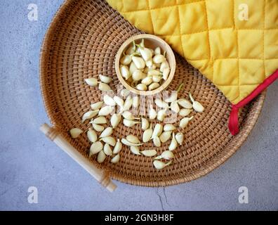 gros plan de la culture de la jarlics dans la tasse en bois et de couleur jaune gant de cuisine dans le panier en rotin tissage sur le sol en ciment Banque D'Images