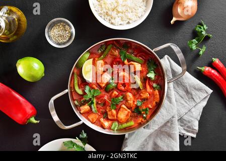 Curry de poulet rouge de style thaïlandais avec légumes dans une casserole sur fond de pierre noire. Vue de dessus, plan d'appartement Banque D'Images