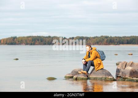 Homme caucasien assis sur le rocher en face du lac et appréciant la vue. Homme se reposant après une longue marche - image Banque D'Images