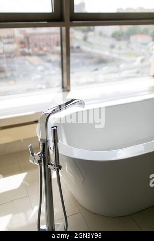 Salle de bain blanche et pure avec baignoire séparée.Salle de bains avec grandes fenêtres Banque D'Images