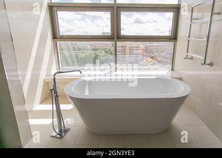 Salle de bain blanche et pure avec baignoire séparée.Salle de bains avec grandes fenêtres Banque D'Images