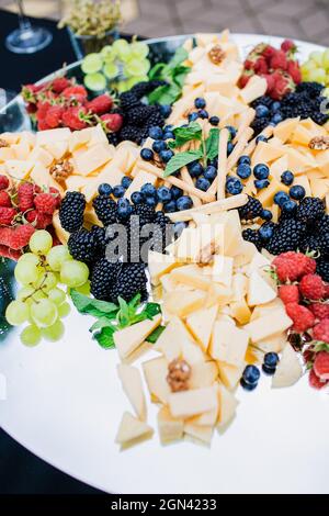 Assiette de fromages servie avec des raisins, de la confiture, des figues, des craquelins et des noix. Banque D'Images