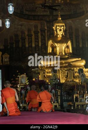 Bangkok, Thaïlande - 15 novembre 2020 : les moines bouddhistes assis priant et de payer respect image de Bouddha dans le vihan principal. Chant du soir. Mise au point et flou. Banque D'Images