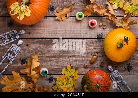 Citrouille d'Halloween. Décoration automnale festive composée de citrouilles, de feuilles, d'araignées, de squelettes et d'yeux amusants sur fond de bois ancien. Composition d'automne Flat Lay Banque D'Images