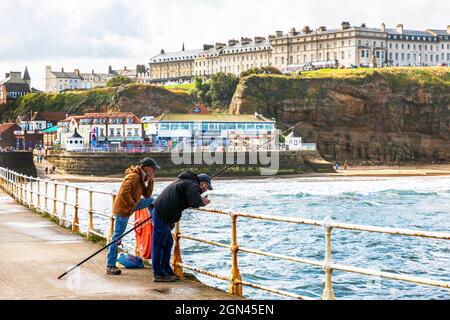 Deux pêcheurs pêchent sur la jetée de Whitby, dans le North Yorkshire, en Angleterre, au Royaume-Uni Banque D'Images