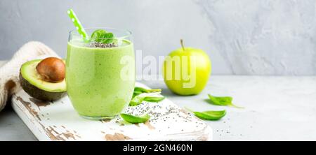 Smoothie vert sain végétarien à base d'avocat, de feuilles d'épinards, de graines de pomme et de chia en verre sur fond de béton gris. Mise au point sélective. Espace pour Banque D'Images