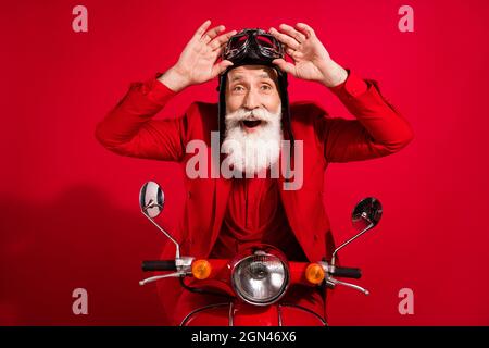Photo de l'âge assez impressionné gentleman porter le nouveau costume de l'année coiffeur équitation bras moto lunettes isolé rouge couleur fond Banque D'Images