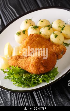 Poulet pané autrichien pané Wiener Backhendl aux pommes de terre bouillies, dans l'assiette de la table. Verticale Banque D'Images