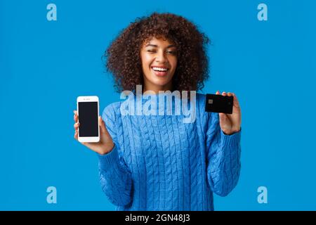 Ne gaspillez pas votre temps d'attente debout, payer en ligne. Atmosphère détendue et chill beau affirmer smiling african american woman montrant l'écran du smartphone Banque D'Images