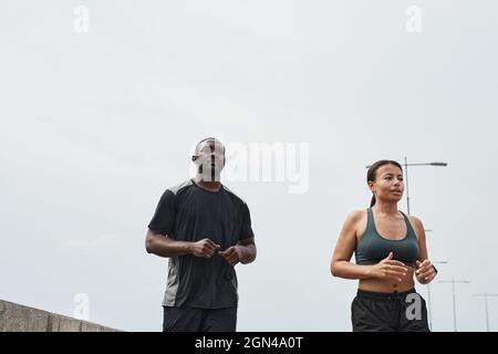 Un jeune couple africain court ensemble le matin à l'extérieur contre le ciel bleu Banque D'Images