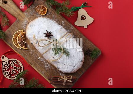 Noël savoureux stollen avec des fruits secs, des baies et des noix sur fond rouge. Gâteries traditionnelles allemandes. Format horizontal. Vue de dessus. Espace pour le texte Banque D'Images