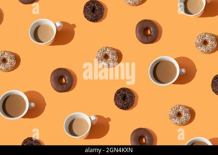 Concept alimentaire créatif composé de beignets au chocolat, café dans une tasse blanche. Motif sucré. Gâteaux et boissons sur fond orange. Par le haut. Plat Banque D'Images