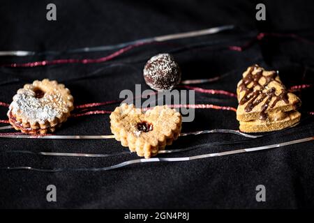 Petit gâteau de noël sur velours noir avec fil rouge et argent. Banque D'Images