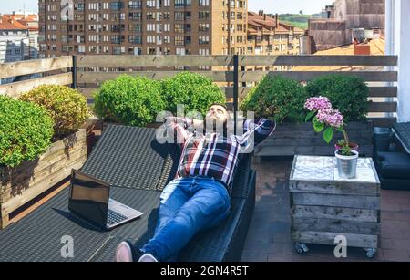 Homme d'affaires reposant sur une chaise longue sur la terrasse Banque D'Images