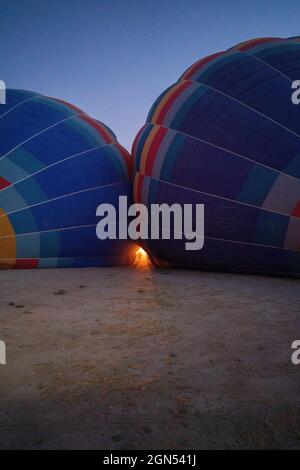 Un équipage debout entre les deux ballons d'air chaud partiellement rempli ou un ballon nouvellement gonflé dans l'obscurité du matin à la cappadoce en Turquie Banque D'Images