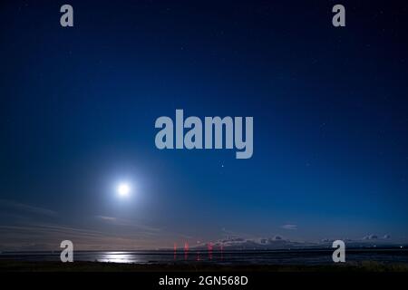 La Lune qui surplombe la côte de Cumbrie et la station de radio Anthorn, prise de Powfoot sur la côte de Dumfries et Galloway Banque D'Images