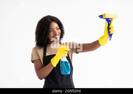 Jeune femme africaine attirante en gants de caoutchouc avec spray et chiffon isolé sur fond blanc Banque D'Images