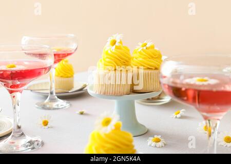 Délicieux cupcakes, verres de boisson et fleurs de camomille sur la table dans la chambre Banque D'Images