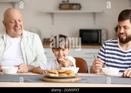 Homme heureux, son petit fils et son père prenant le petit déjeuner dans la cuisine Banque D'Images