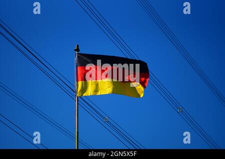 FRANCFORT, ALLEMAGNE - 14 juin 2021 : drapeau allemand devant les lignes haute tension. Contraste ensoleillé avec un ciel bleu ensoleillé. Approvisionnement énergétique allemand. Banque D'Images