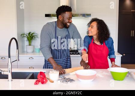 Heureux couple afro-américain portant des tabliers, cuisant ensemble Banque D'Images