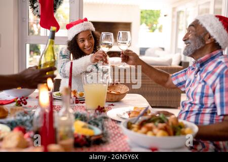 Bonne fille adulte afro-américaine et son père senior font des toasts à la table de noël Banque D'Images