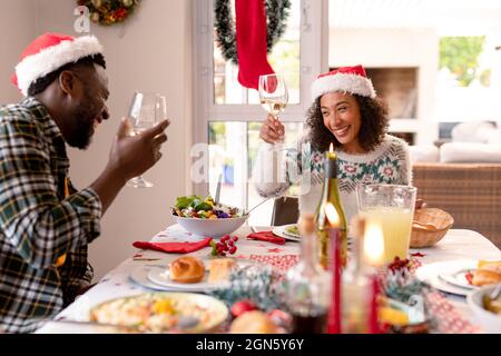 Joyeux couple afro-américain qui fait du pain grillé à la table de noël Banque D'Images