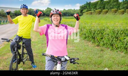 Heureux asiatique en bonne santé couple senior s'exerçant avec des vélos Banque D'Images