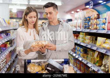 Jeune couple aimant faire des achats ensemble, en choisissant des biscuits dans l'épicerie Banque D'Images