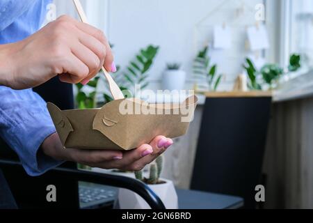 Femme d'affaires ayant une pause déjeuner saine à partir de boîtes à déjeuner écologiques livrées. Concept de nourriture équilibrée et délicieuse. Bureau à domicile. Vaisselle écologique sans gaspillage. Livraison de nourriture Banque D'Images