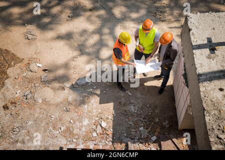 Équipe de travailleurs de la construction discutant des détails du projet avec le superviseur exécutif du chantier de construction. Banque D'Images
