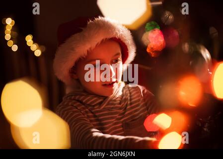 Portrait d'un garçon de 8 ans décorant l'arbre de Noël Banque D'Images