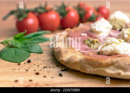 Gros plan de la pizza italienne sur une planche à découper en bois. Sur fond tomates et basilic défocused. Banque D'Images