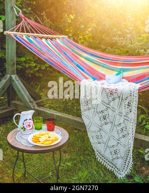 Coin détente dans le jardin. Cadre extérieur en été. Hamac. Tranches d'orange, de verres et de carafe sur une petite table basse. Banque D'Images