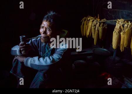 Un chasseur national Chin à la retraite assis à côté de sa cuisine et fuyant le pipe. Banque D'Images