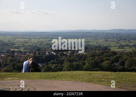 Un couple se câlin sur Glastonbury Tor, avec des vues à travers Somerset au Royaume-Uni Banque D'Images