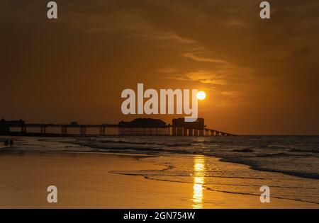 Vue sur le coucher du soleil sur la jetée de Cromer montrant l'extrémité du théâtre de la jetée et la station de bateau de sauvetage RNLI, Cromer, Norfolk, Royaume-Uni Banque D'Images