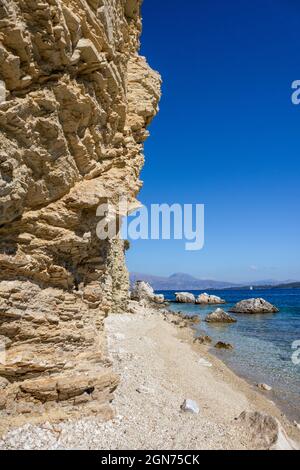 Falaises rocheuses blanches sur la plage de galets avec l'eau claire d'azur et les montagnes à distance sur la côte de l'île de Lefkada en Grèce. Été nature sauvage voyage à Banque D'Images